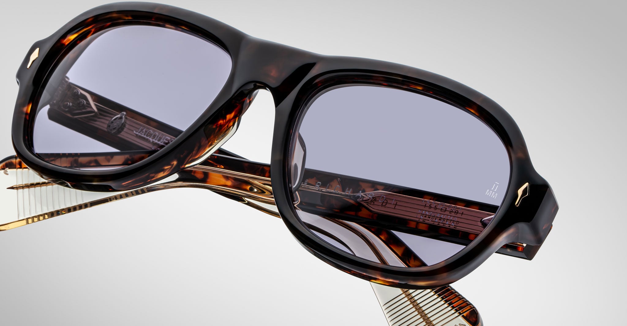 Detailed front view of a pair of Jacques Marie Mage Richard Havana, thick-framed sunglasses with blue lenses on a plain background