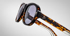 Detailed profile view of a pair of Jacques Marie Mage Richard Havana, thick-framed sunglasses with blue lenses on a plain background