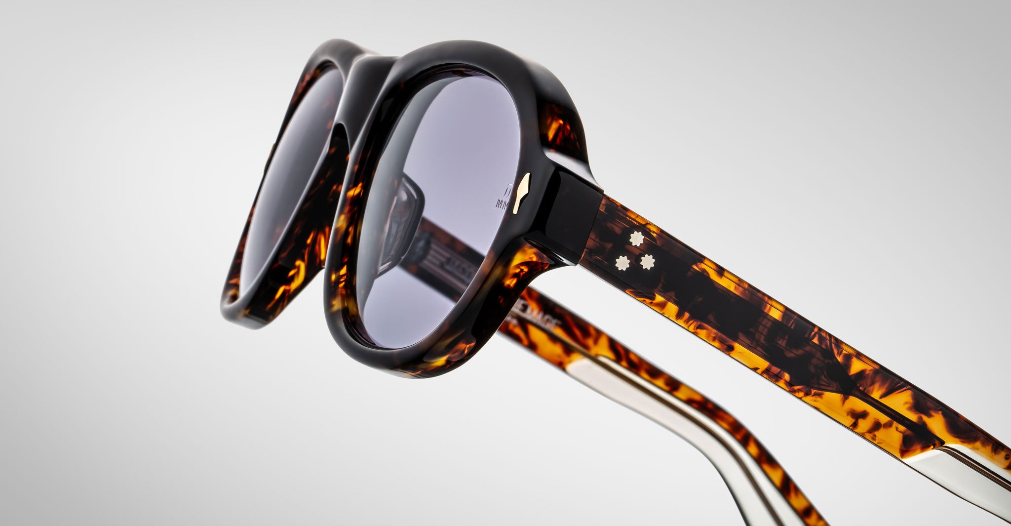 Detailed profile view of a pair of Jacques Marie Mage Richard Havana, thick-framed sunglasses with blue lenses on a plain background