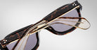 Detailed back view of a pair of Jacques Marie Mage Richard Havana, thick-framed sunglasses with blue lenses on a plain background