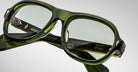 A close-up of green translucent Jacques Marie Mage Richard eyeglasses with clear lenses, gold accents, and visible branding on the arms, including JACQUES, RICHARD, and MADE IN JAPAN.