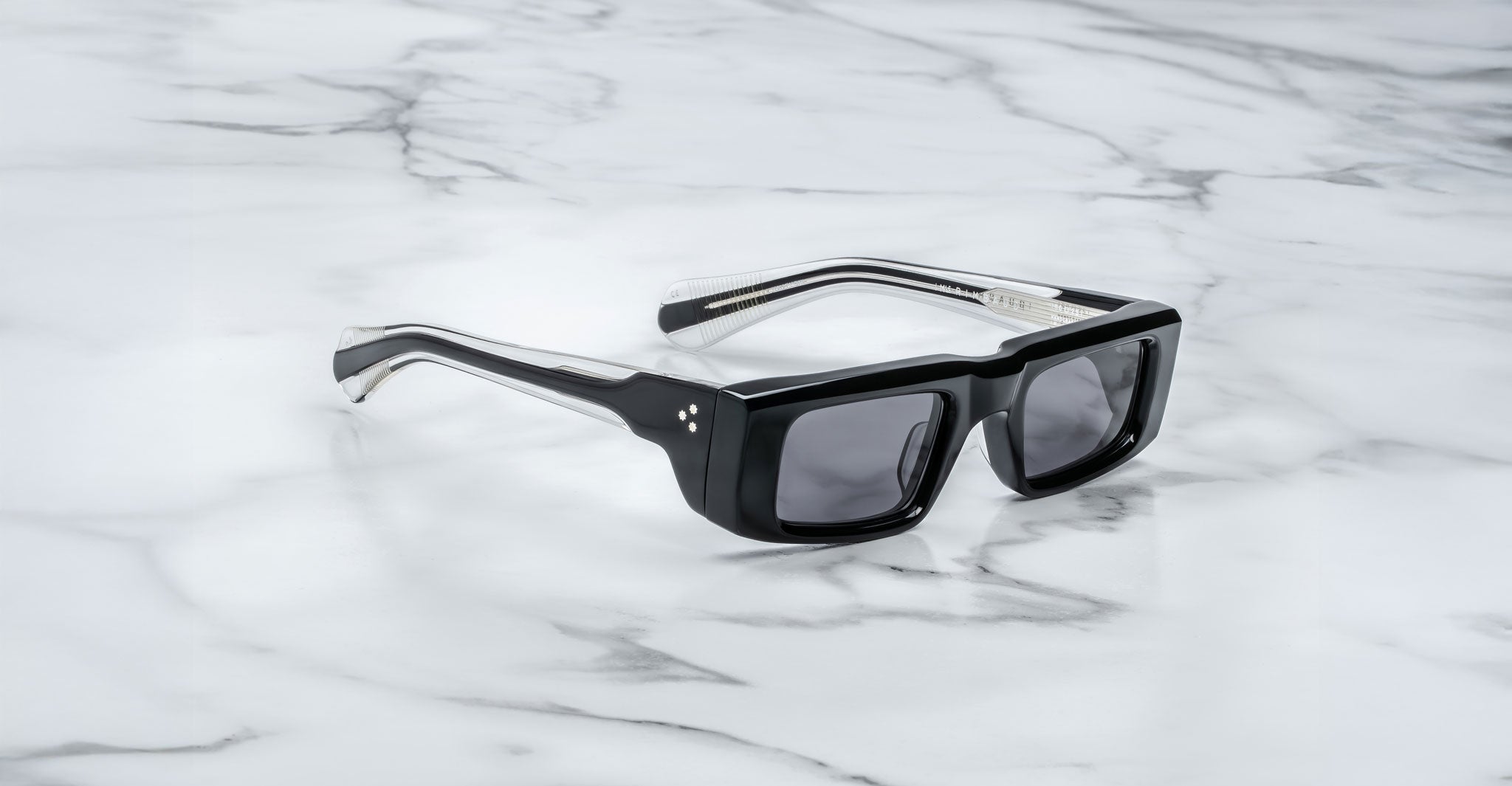 Front view of the Jacques Marie Mage Rimbaud sunglass in black color with grey lenses on a white marbled with grey veining background