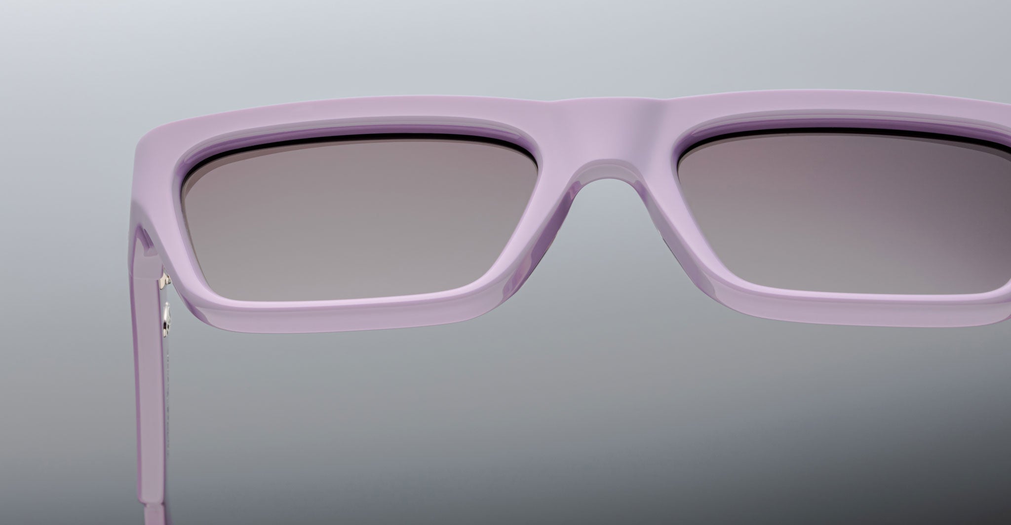 Close-up of the Jacques Marie Mage Rush rectangular sunglasses with thick light purple frames and dark tinted lenses against a neutral gray background.