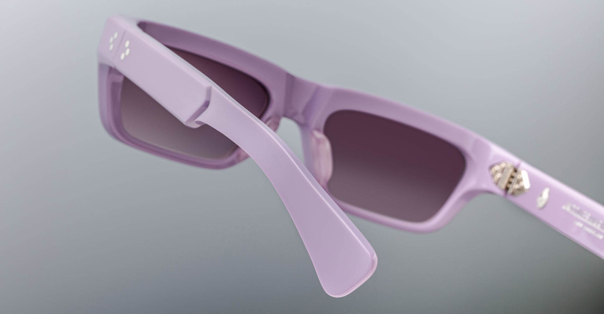 Close-up of the back of Jacques Marie Mage Rush rectangular sunglasses in pastel purple with dark lenses, highlighting the thick arms and a small silver emblem inside the right arm.