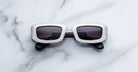 Jacques Marie Mage Ryder in Silver, rectangular silver-tone acetate sunglasses with thick sculpted rims, a low-profile bridge, and gradient tinted lenses, shown front-facing on a light marble surface.