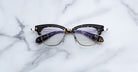 A pair of Jacques Marie Mage Sartre eyeglasses with clear lenses is displayed elegantly on a white marble surface.