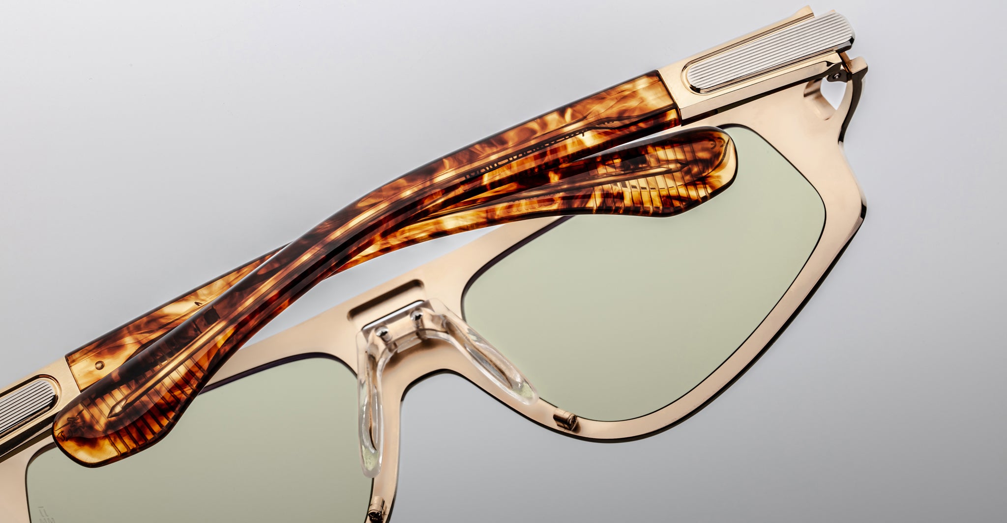 Close-up of Jacques Marie Mage Scarface sunglasses featuring light green lenses and tortoiseshell arms, viewed from the side.