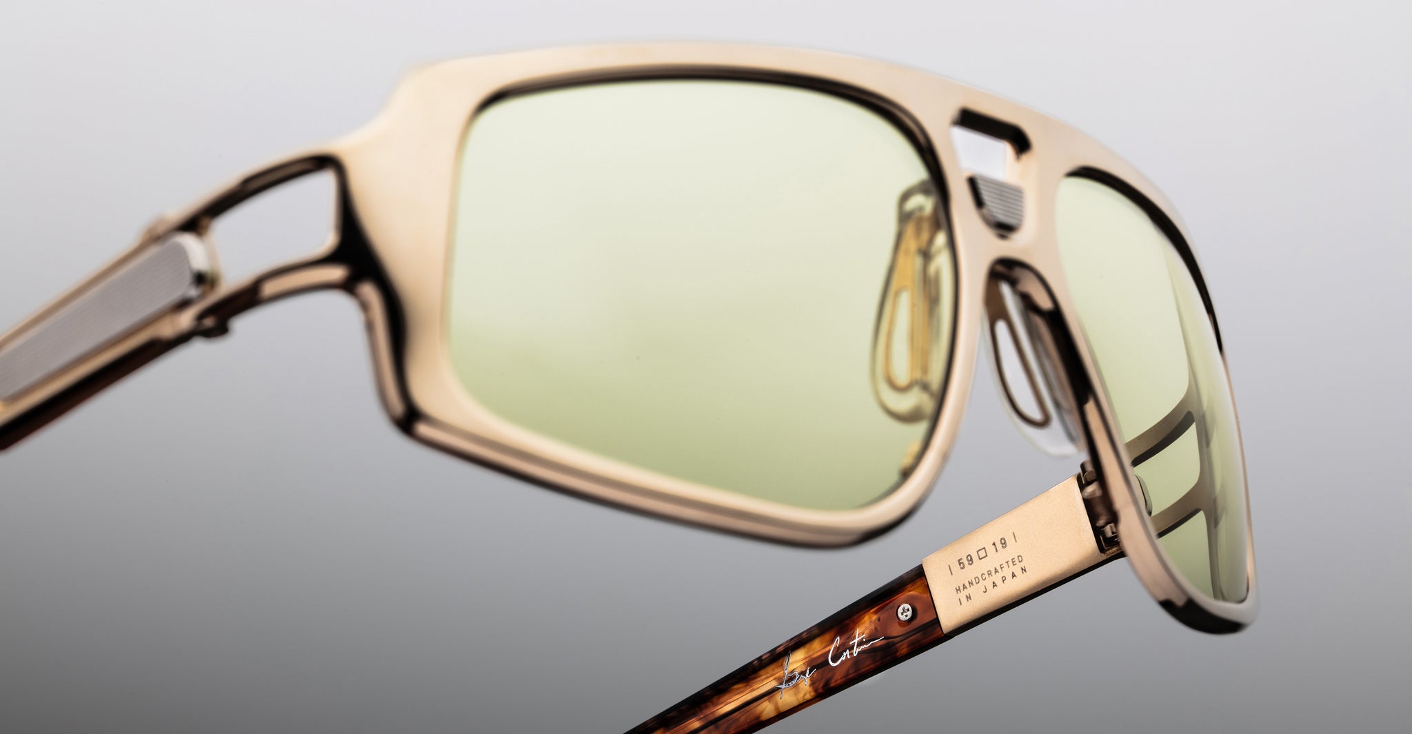 Jacques Marie Mage Scarface sunglasses with gold frames, light green lenses, and tortoiseshell arms shown from a front angle.