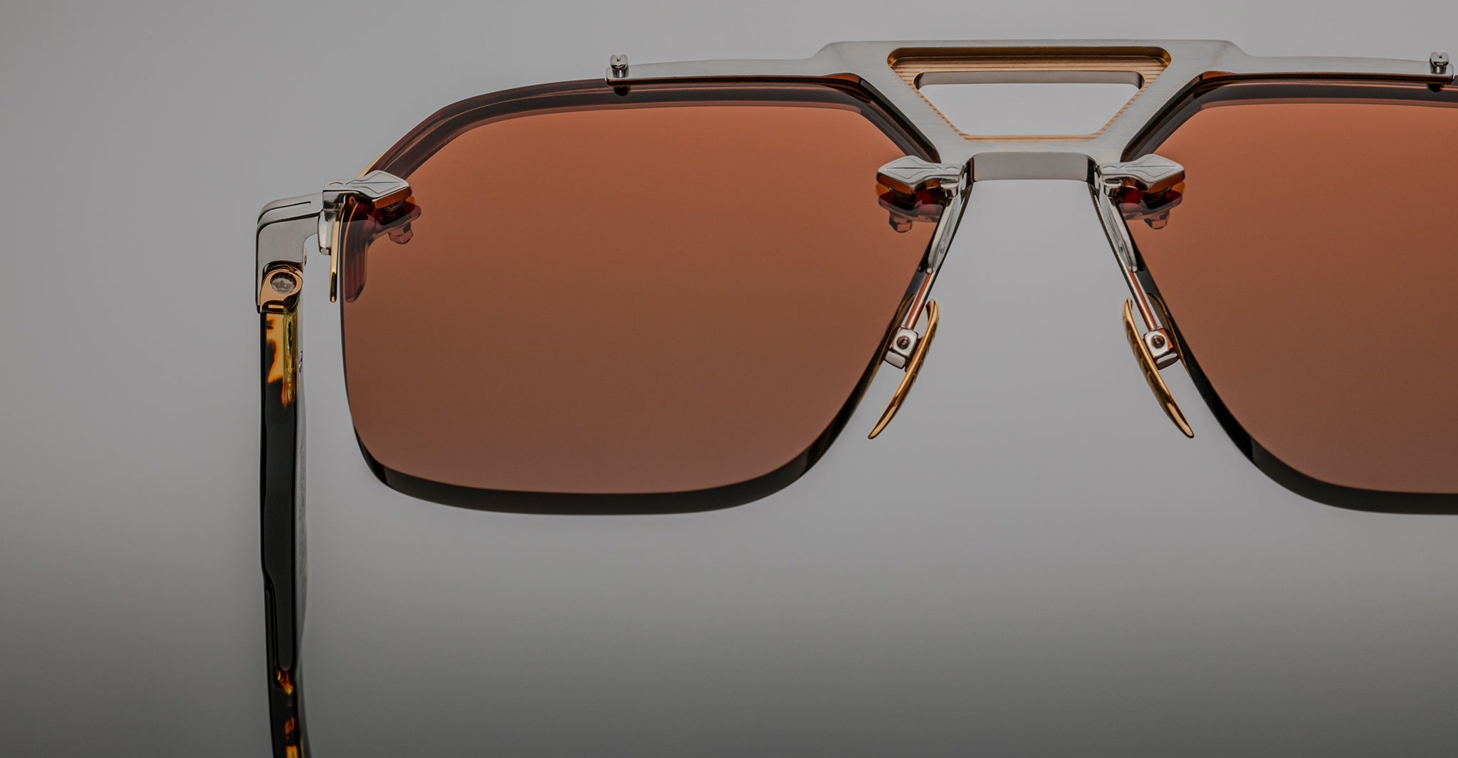 Close-up view of Jacques Marie Mage Silverton designer sunglasses featuring geometric metal frames and reddish-brown tinted rectangular lenses, set against a neutral background.