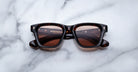 Jacques Marie Mage Sonata tortoiseshell rectangular sunglasses with brown lenses shown from above on a flat surface.