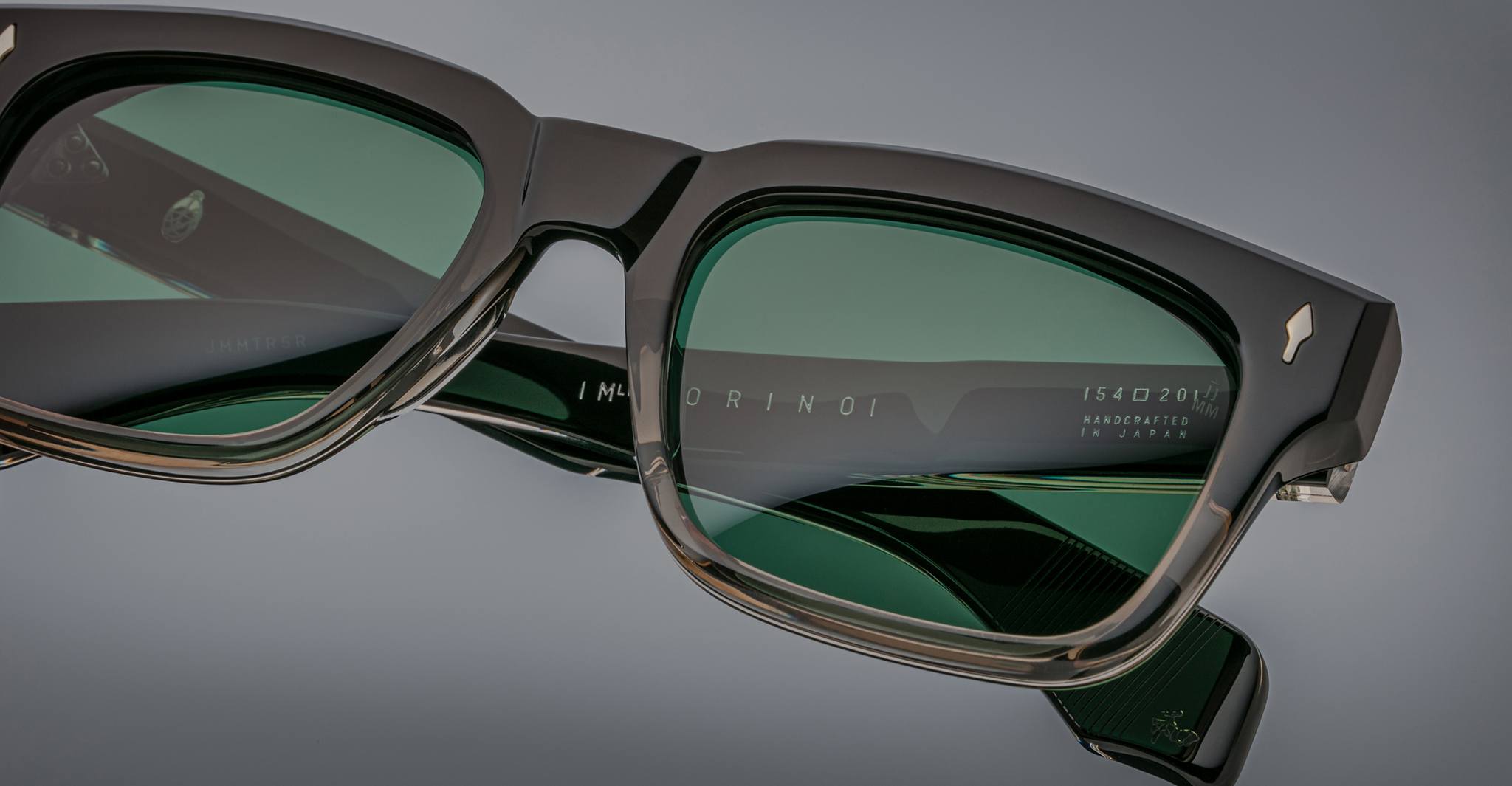 Close-up of Jacques Marie Mage Torino rectangular frames in green-tinted acetate, highlighting detailed text and expert craftsmanship on the temple and lens—a hallmark of Jacques Marie Mage handcrafted eyewear.