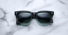 Jacques Marie Mage Torino: Bold, handcrafted black rectangular sunglasses with dark lenses by Jacques Marie Mage, styled on a white marble surface.