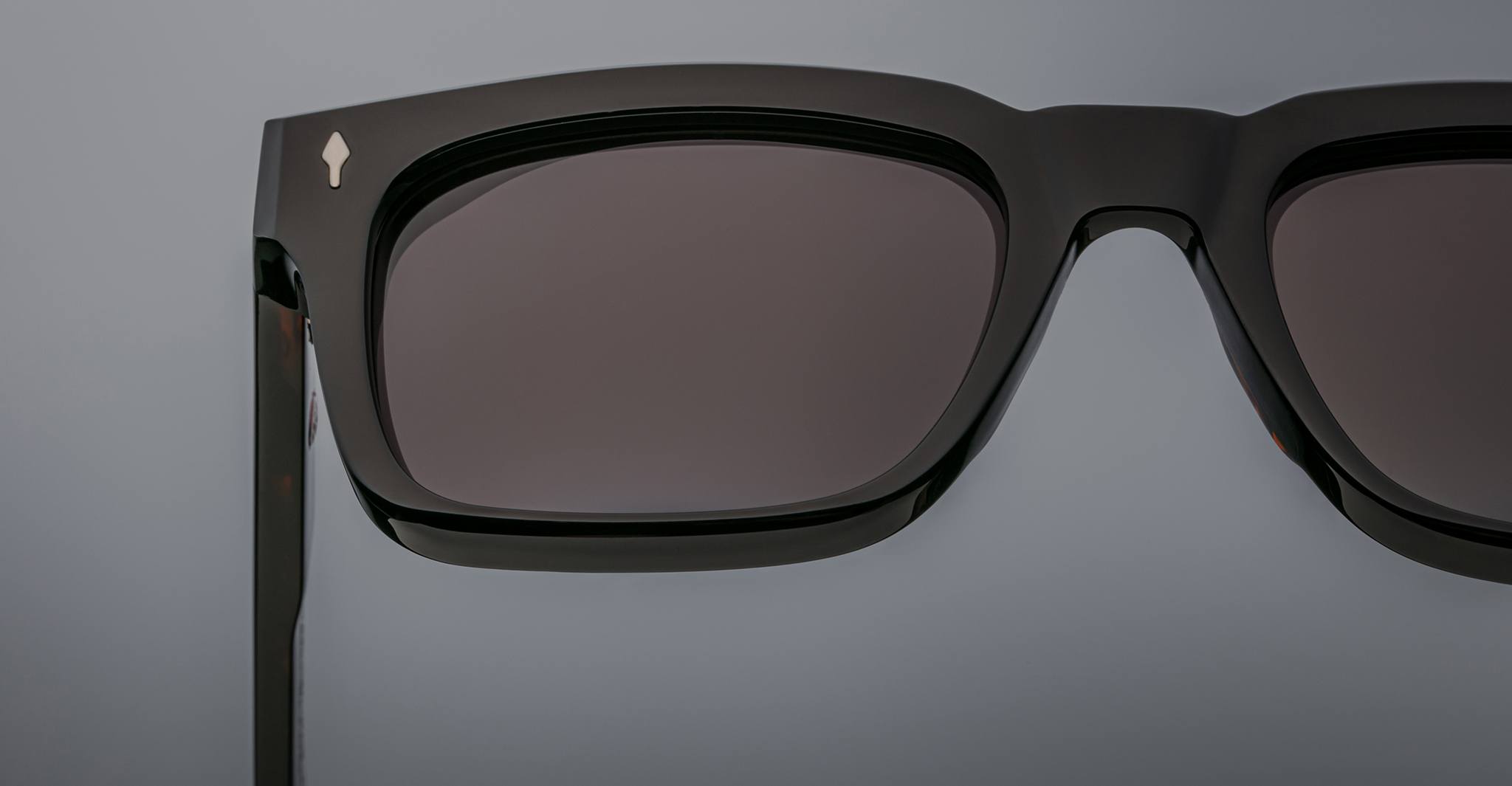 Close-up of Jacques Marie Mage Torino sunglasses featuring bold rectangular black acetate frames, dark lenses, and hinges, set against a neutral background.