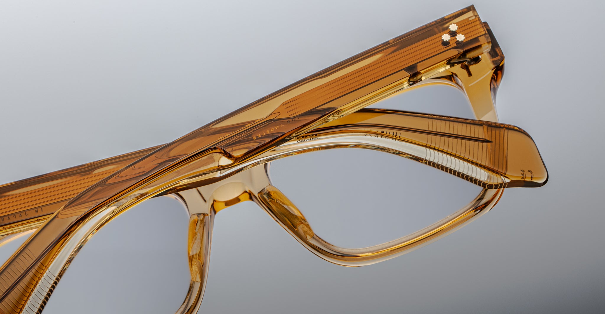 Close-up of two pairs of Jacques Marie Mage Torino eyeglass frames, featuring bold rectangular shapes and handcrafted acetate, stacked together against a plain background.