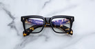 Jacques Marie Mage Torino in Borneo Tavern tortoise optical frame, front view with lights reflected in lenses on a white marble surface.