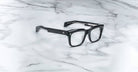 Jacques Marie Mage Torino bold rectangular eyeglass frames, handcrafted in acetate by Jacques Marie Mage, are displayed elegantly on a white marble surface with gray veining.