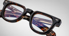Close-up of Jacques Marie Mage Vendome optical frames, handcrafted in Japan with a tortoiseshell rectangular design and brand markings on the frame and temples, set against a plain light background.