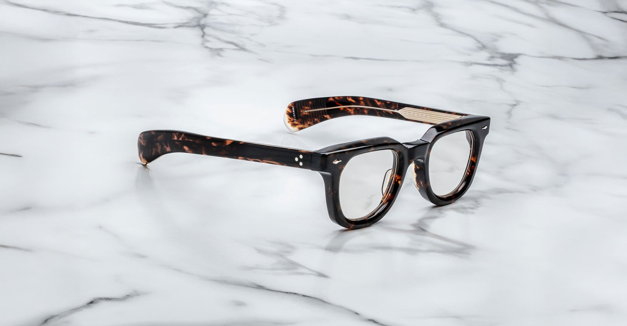 A pair of Jacques Marie Mage Vendome optical frames, featuring a dark tortoiseshell finish and thick design, rests on white marble. Handcrafted in Japan by Jacques Marie Mage.