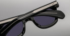 Close-up of Jacques Marie Mage Vendome sunglasses by Jacques Marie Mage, featuring black frames with silver temple detailing, handcrafted in Japan, displayed on a plain grey background.