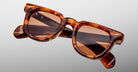 Jacques Marie Mage Vendome tortoiseshell rectangular sunglasses with brown tinted lenses, handcrafted in Japan, are displayed against a light gray background.
