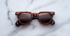 Jacques Marie Mage Vendome tortoiseshell rectangular sunglasses, handcrafted in Japan, rest on a white marble surface.