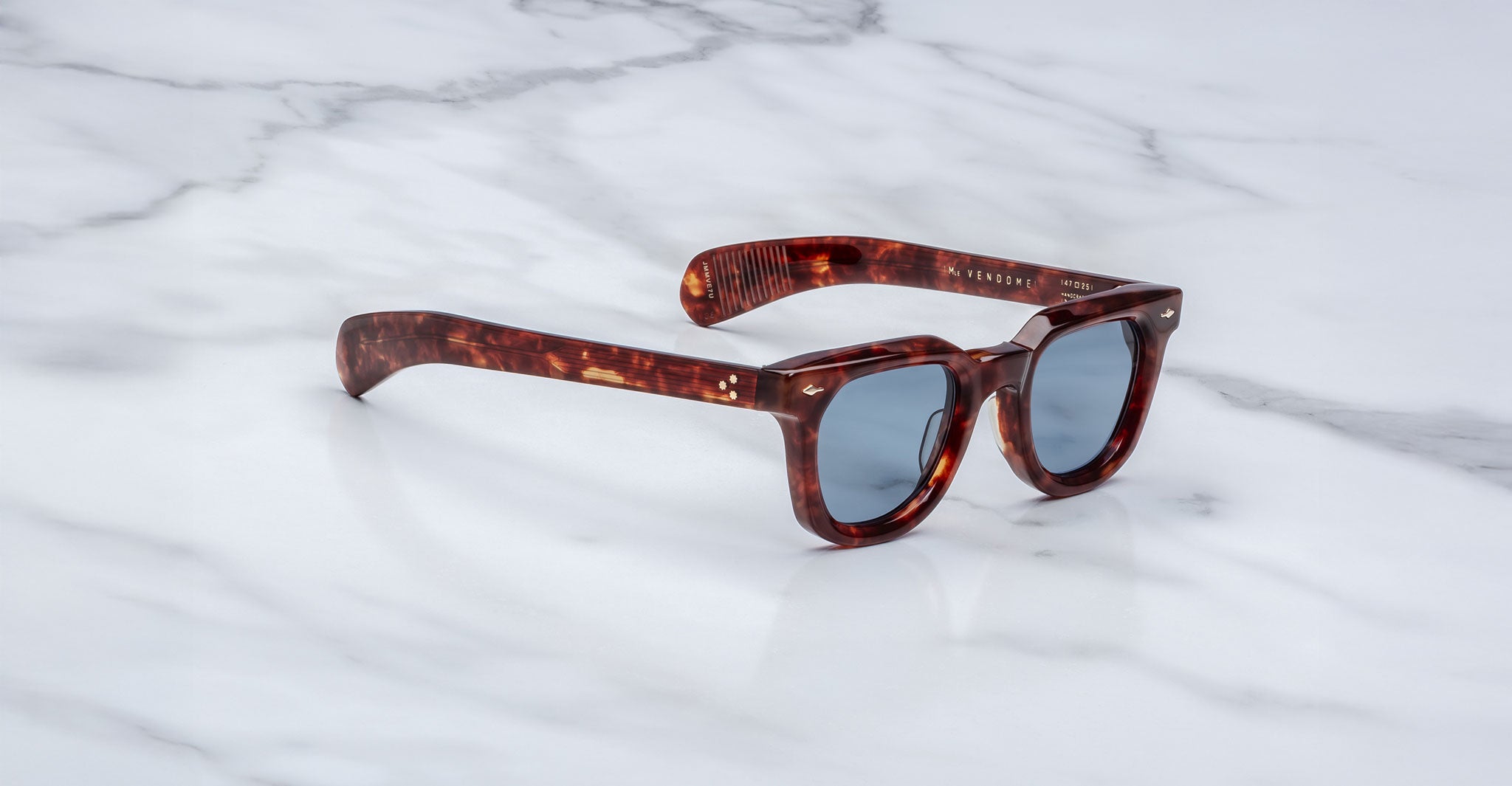 Jacques Marie Mage Vendome sunglasses in tortoiseshell with dark lenses are displayed on a white marble surface.