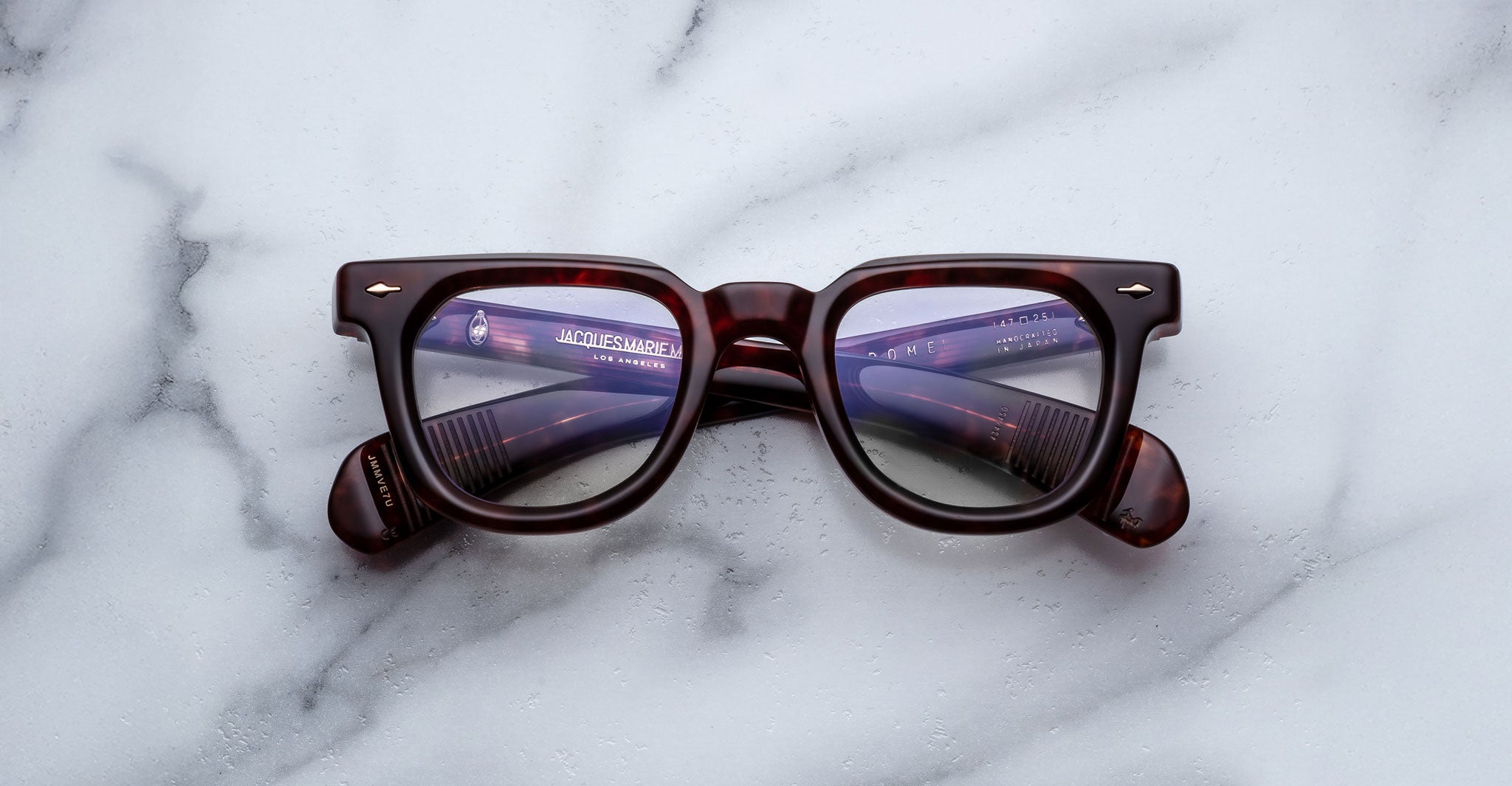 Jacques Marie Mage Vendome brown tortoiseshell optical frames, handcrafted in Japan, are displayed on white marble with gray veins.