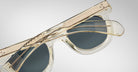 Partially folded Jacques Marie Mage Vendome sunglasses with translucent frames and dark lenses are displayed against a plain light background.
