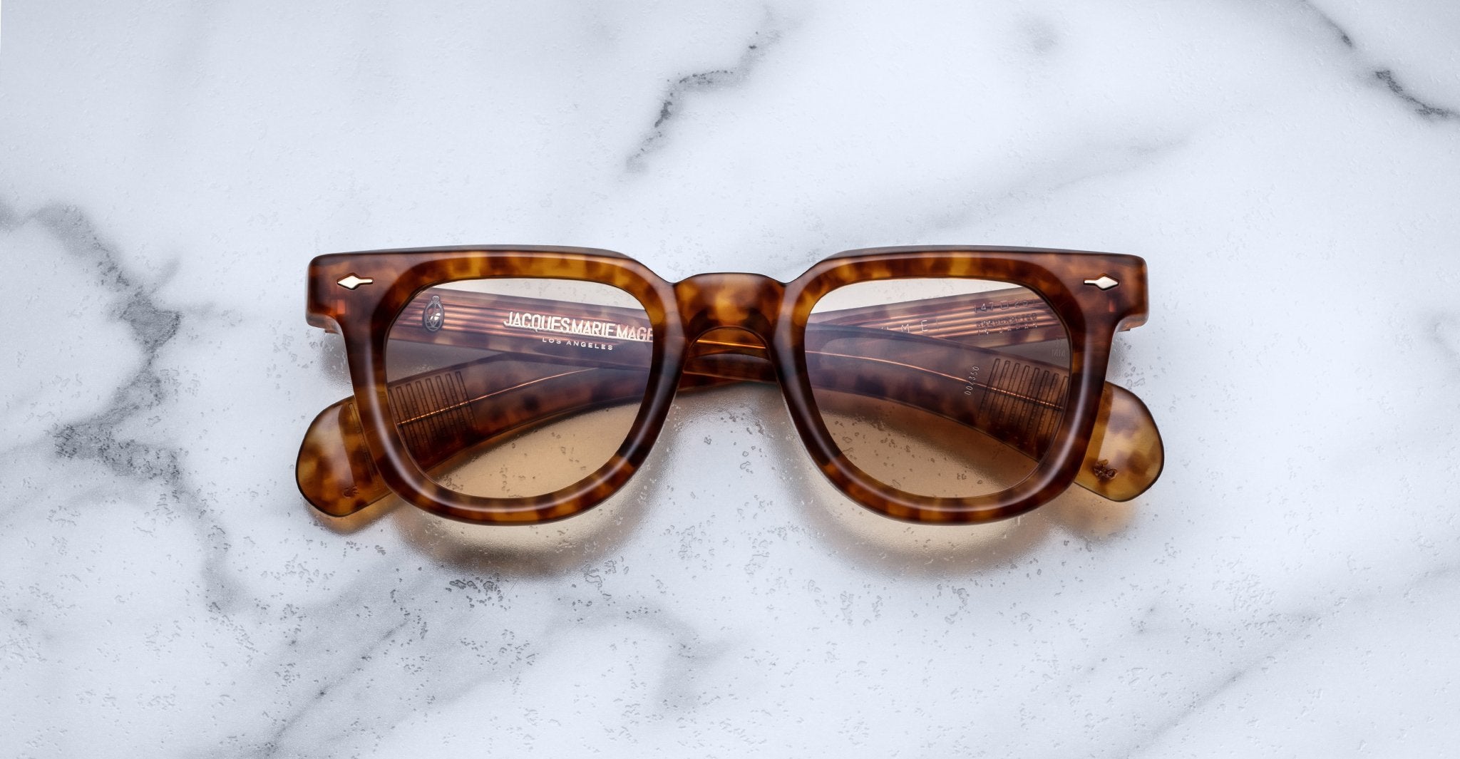 Jacques Marie Mage Vendome sunglasses by Jacques Marie Mage, featuring brown tortoiseshell rectangular frames, handcrafted in Japan, elegantly displayed on a white marble surface.