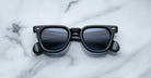 Jacques Marie Mage Vendome black rectangular sunglasses with dark lenses, handcrafted in Japan by Jacques Marie Mage, shown on a white marble surface.