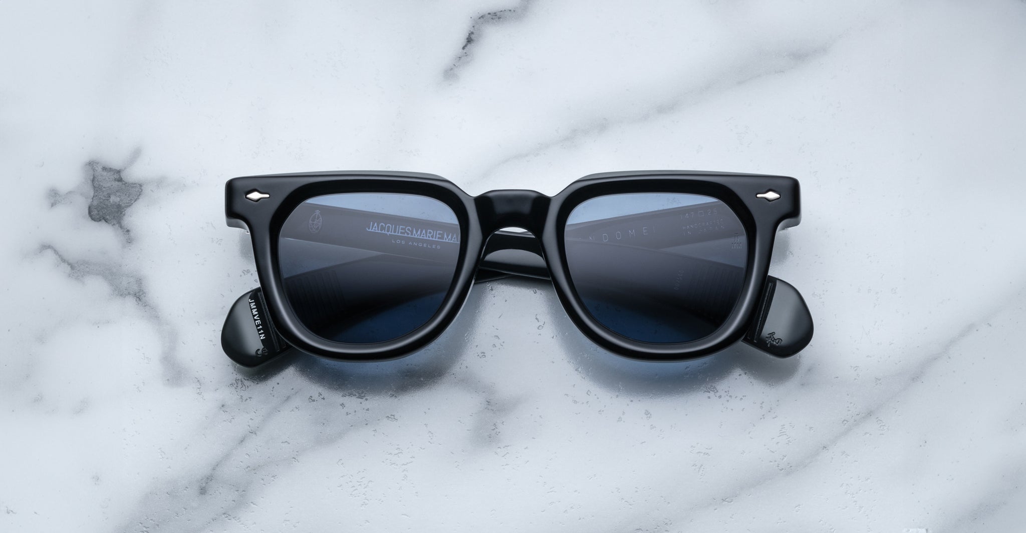 Jacques Marie Mage Vendome black rectangular sunglasses with dark lenses, handcrafted in Japan by Jacques Marie Mage, shown on a white marble surface.