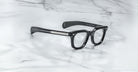 Jacques Marie Mage Vendome black rectangular optical frames with thick temples and silver accents, handcrafted in Japan by Jacques Marie Mage, displayed on a white marble surface.