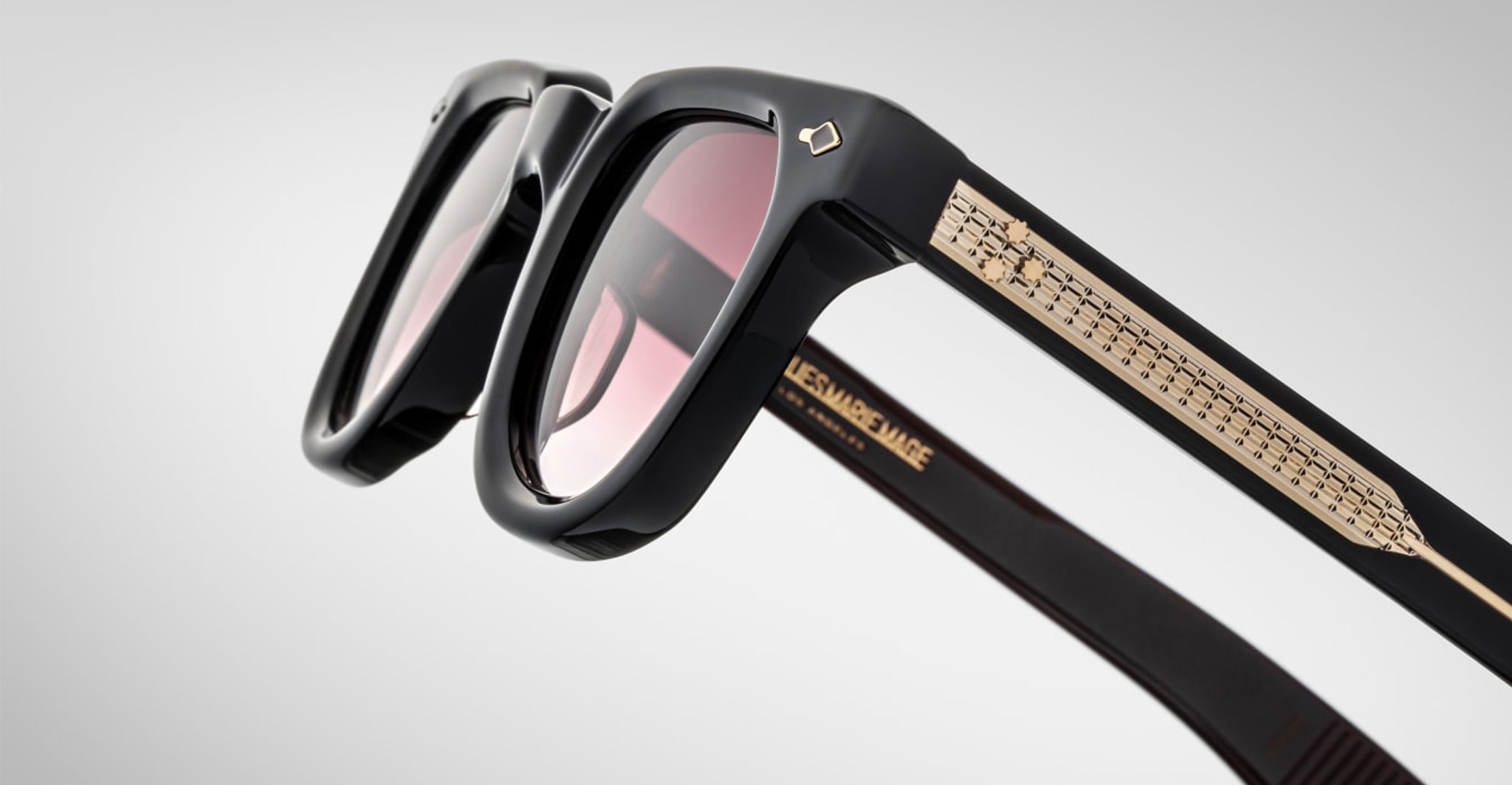 Close-up of Jacques Marie Mage Vendome sunglasses in black with gold-accented arms and tinted lenses, handcrafted in Japan by Jacques Marie Mage, shown against a plain light background.