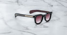 Jacques Marie Mage Vendome sunglasses, handcrafted in Japan with gradient lenses and gold-accented arms, are displayed on a white marble surface.