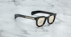 Jacques Marie Mage Vendome sunglasses by Jacques Marie Mage, featuring a black rectangular frame, gold accents, and light lenses, handcrafted in Japan, displayed on white marble.