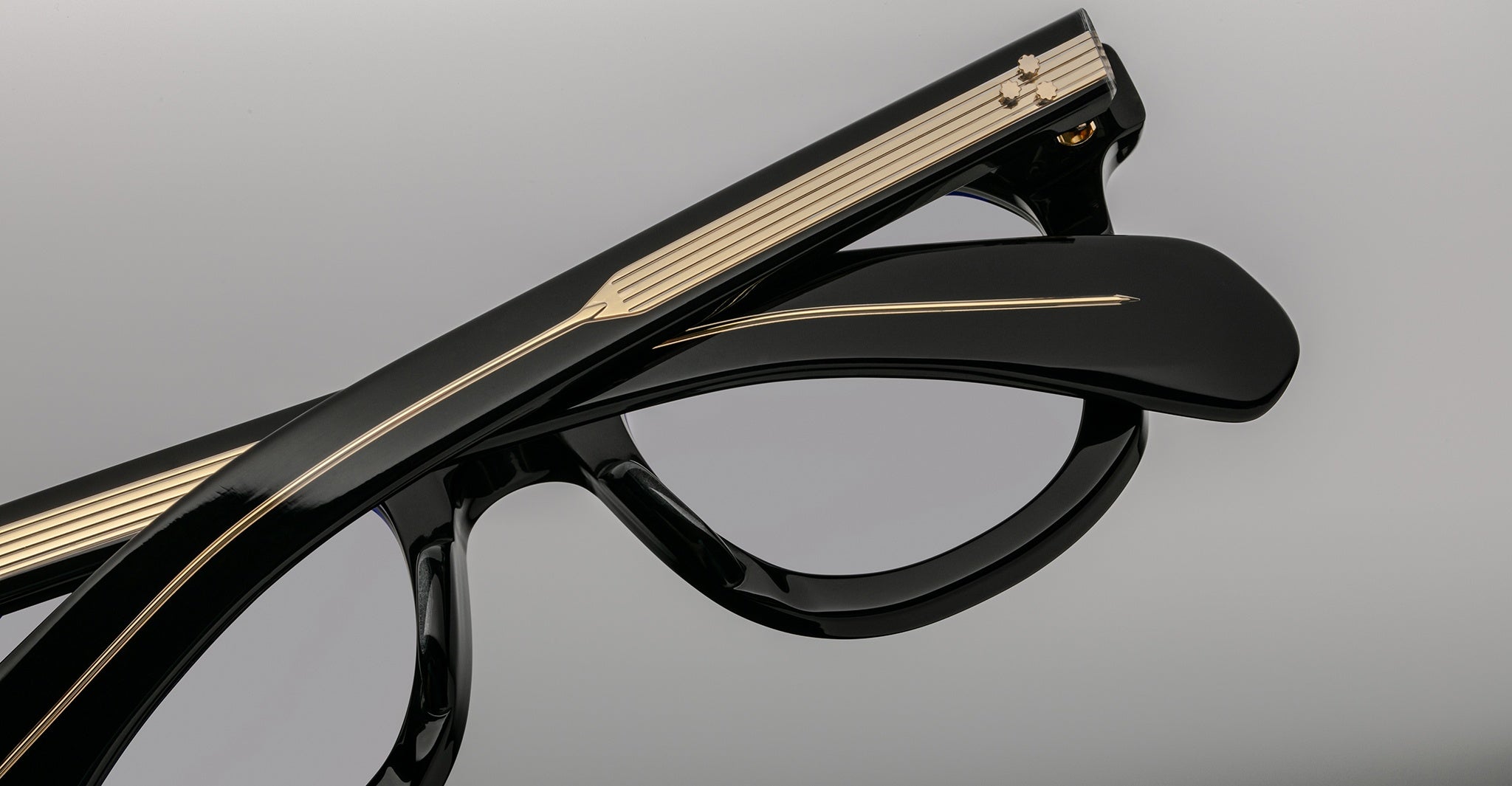 Close-up of Jacques Marie Mage Vendome eyeglasses by Jacques Marie Mage, handcrafted in Japan, featuring black frames with gold arm detailing and one arm folded over the front.