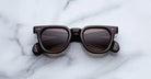 Jacques Marie Mage Vendome in Ganache square-framed sunglasses with black frames and dark lenses, top-down view.