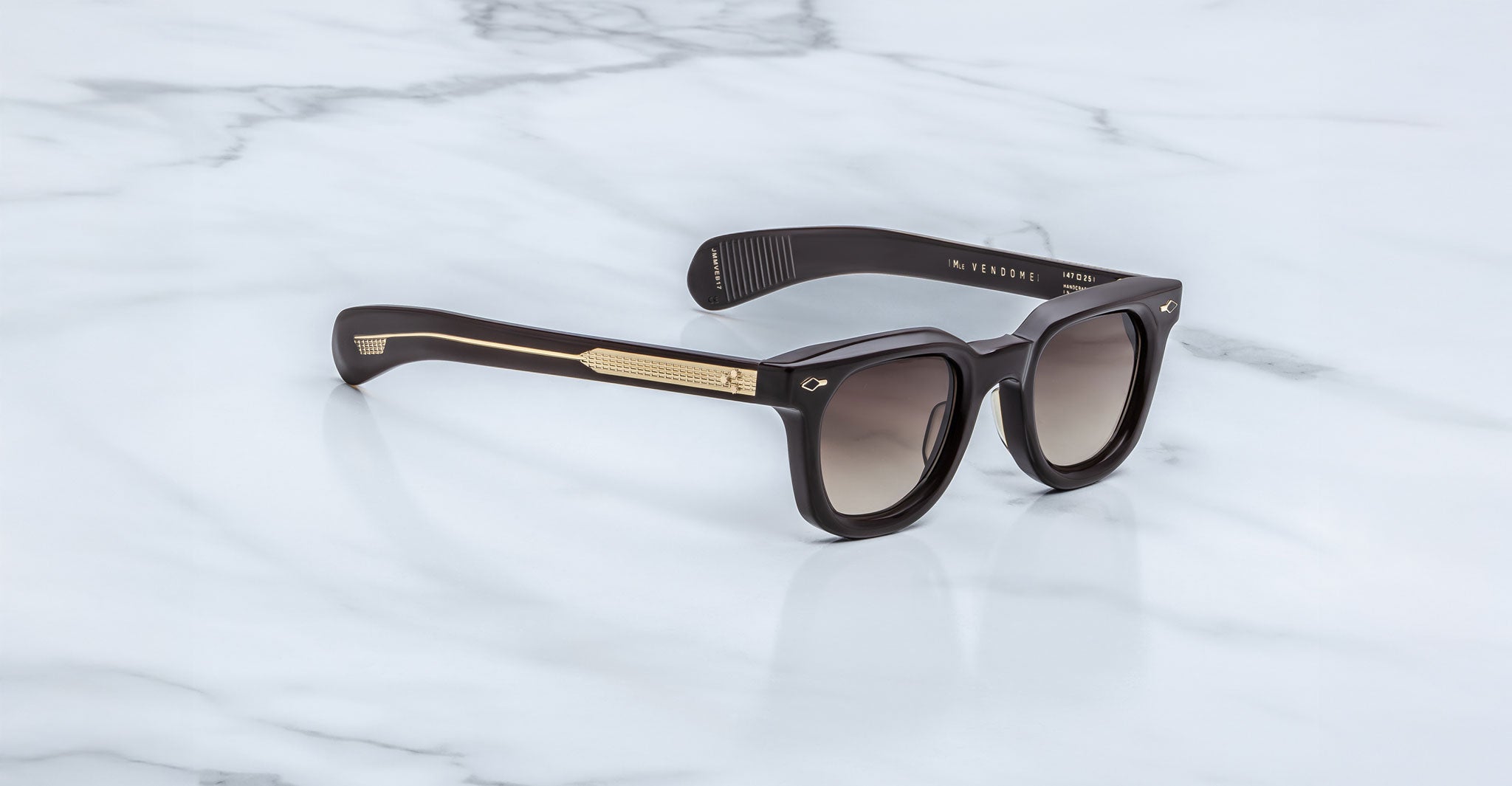 Jacques Marie Mage Vendome black rectangular sunglasses with gold arm detailing, handcrafted in Japan by Jacques Marie Mage, shown on a white marble surface.