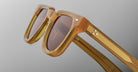 Close-up of Jacques Marie Mage Vendome sunglasses, featuring translucent amber frames, brown lenses, and metallic accents. Handcrafted in Japan by Jacques Marie Mage, shown against a neutral background.
