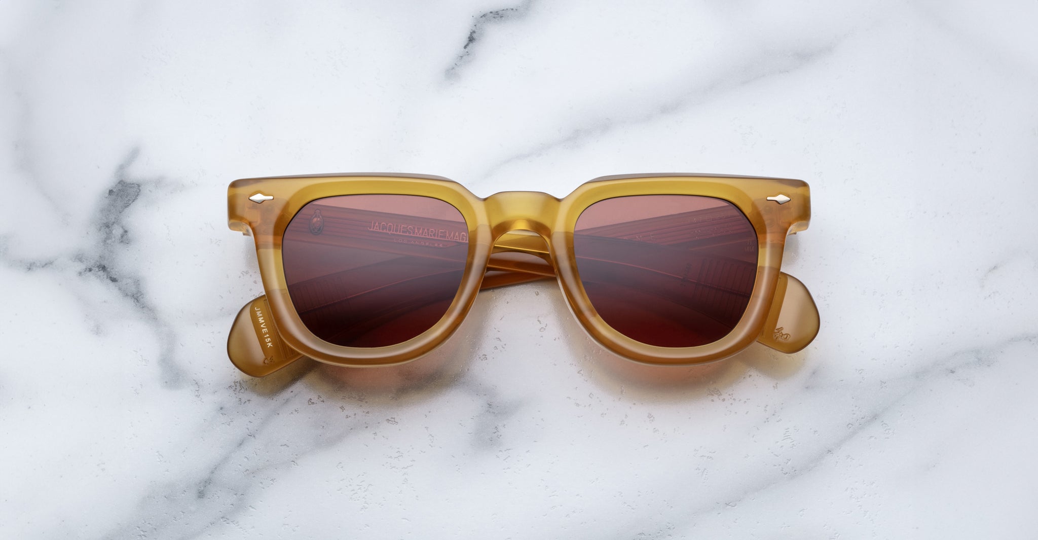 Jacques Marie Mage Vendome sunglasses by Jacques Marie Mage, featuring brown square frames and red-tinted lenses, handcrafted in Japan, shown on a white marble surface.