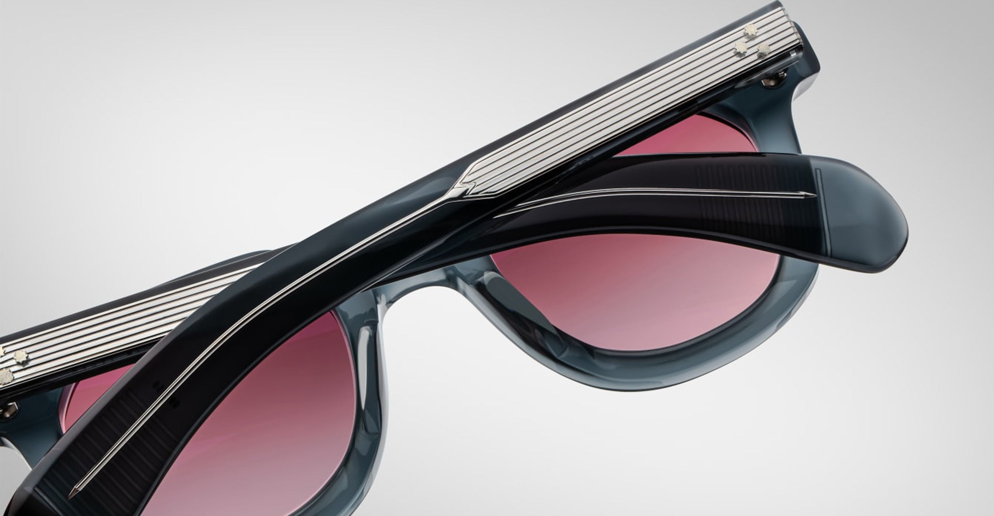 Close-up of Jacques Marie Mage Vendome sunglasses with black frames, silver arm detailing, and pink-tinted lenses—handcrafted in Japan—displayed against a plain background.