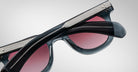 Close-up of Jacques Marie Mage Vendome sunglasses with black frames, silver arm detailing, and pink-tinted lenses—handcrafted in Japan—displayed against a plain background.