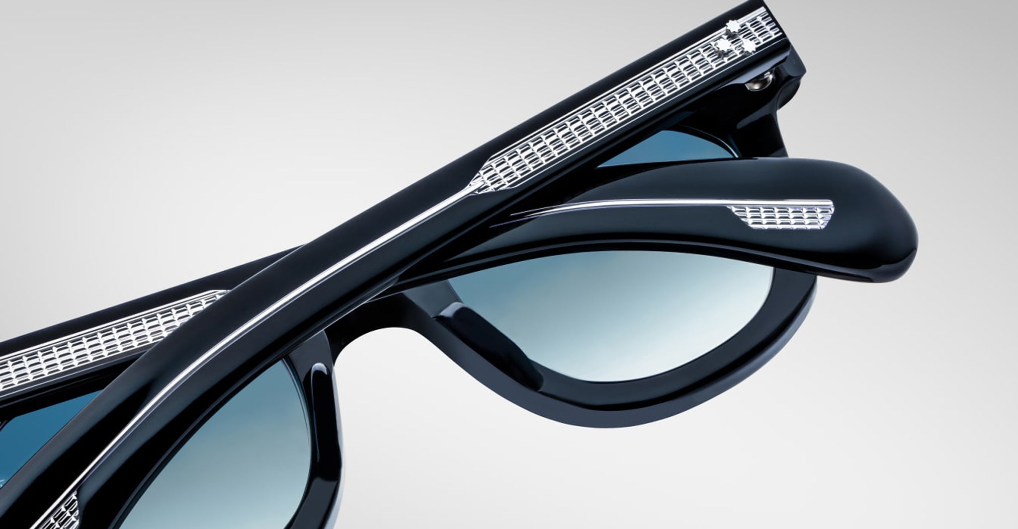 A close-up of two stacked pairs of Jacques Marie Mage Vendome sunglasses, handcrafted in Japan, in black with silver temple detailing, set against a light gray background.