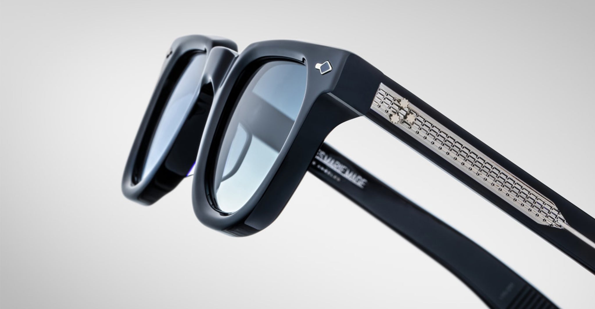 Close-up of Jacques Marie Mage Vendome sunglasses in black, featuring reflective lenses and decorative metallic arm details, handcrafted in Japan by Jacques Marie Mage, set against a plain light background.