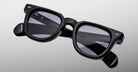 The Jacques Marie Mage Vendome sunglasses by Jacques Marie Mage feature handcrafted black rectangular thick frames and dark tinted lenses, made in Japan, displayed on a plain light gray background.