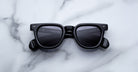 Jacques Marie Mage Vendome, black rectangular sunglasses with thick frames by Jacques Marie Mage, handcrafted in Japan and displayed on a white marble surface.