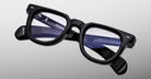 A pair of Jacques Marie Mage Vendome black rectangular optical frames with clear lenses, handcrafted in Japan and featuring branding and model info on the inner arm, is shown against a light gray background.