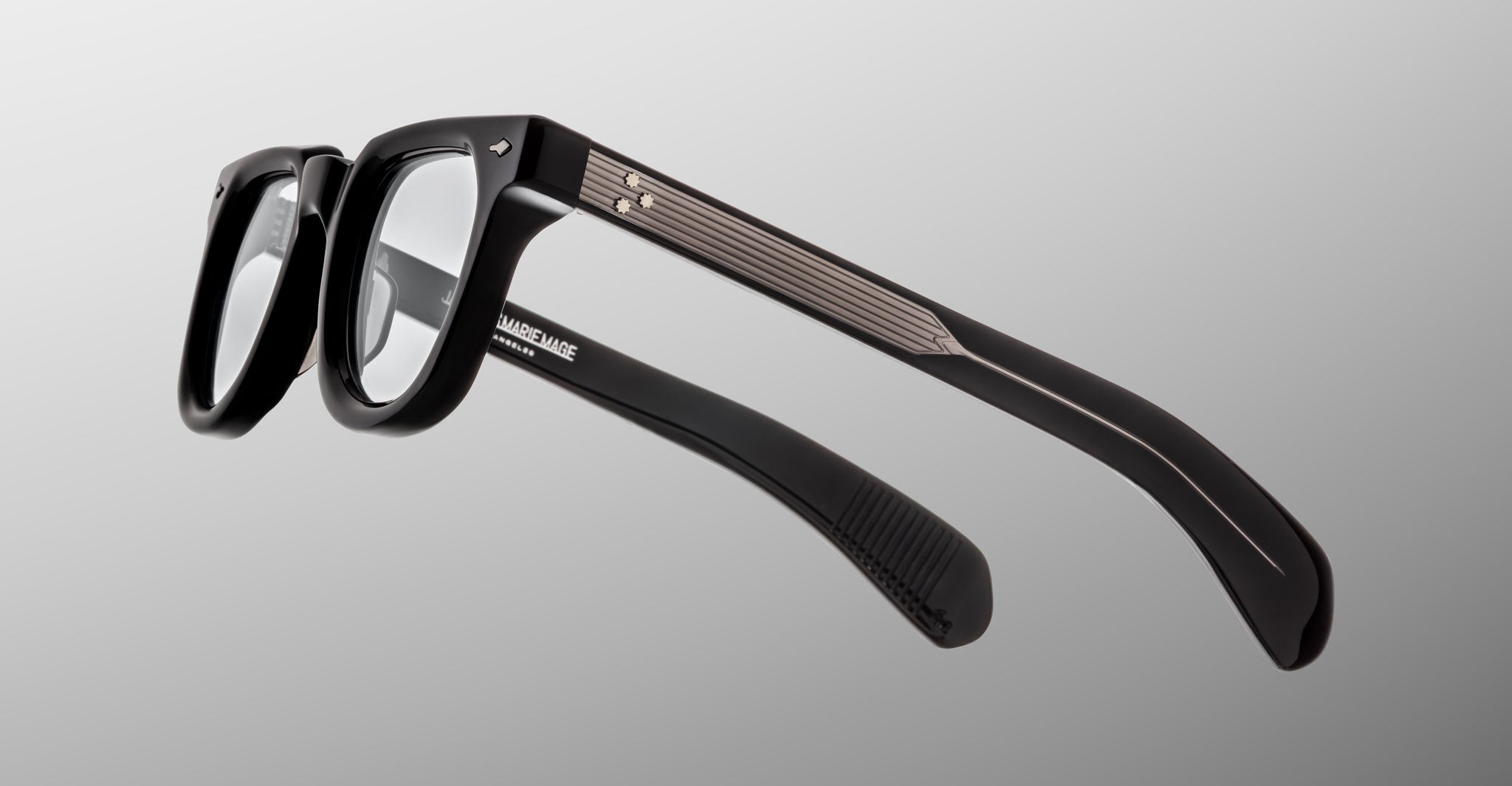Jacques Marie Mage Vendome optical frames feature black rims, clear lenses, and silver temple accents, handcrafted in Japan by Jacques Marie Mage, displayed on a neutral gradient background.