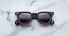 Jacques Marie Mage Vendome sunglasses by Jacques Marie Mage feature black frames and dark tinted lenses, handcrafted in Japan and displayed on a white marble surface.