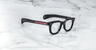 Jacques Marie Mage Vendome optical frames with bold edges and vivid red temples, handcrafted in Japan by Jacques Marie Mage, displayed on a white marble surface.